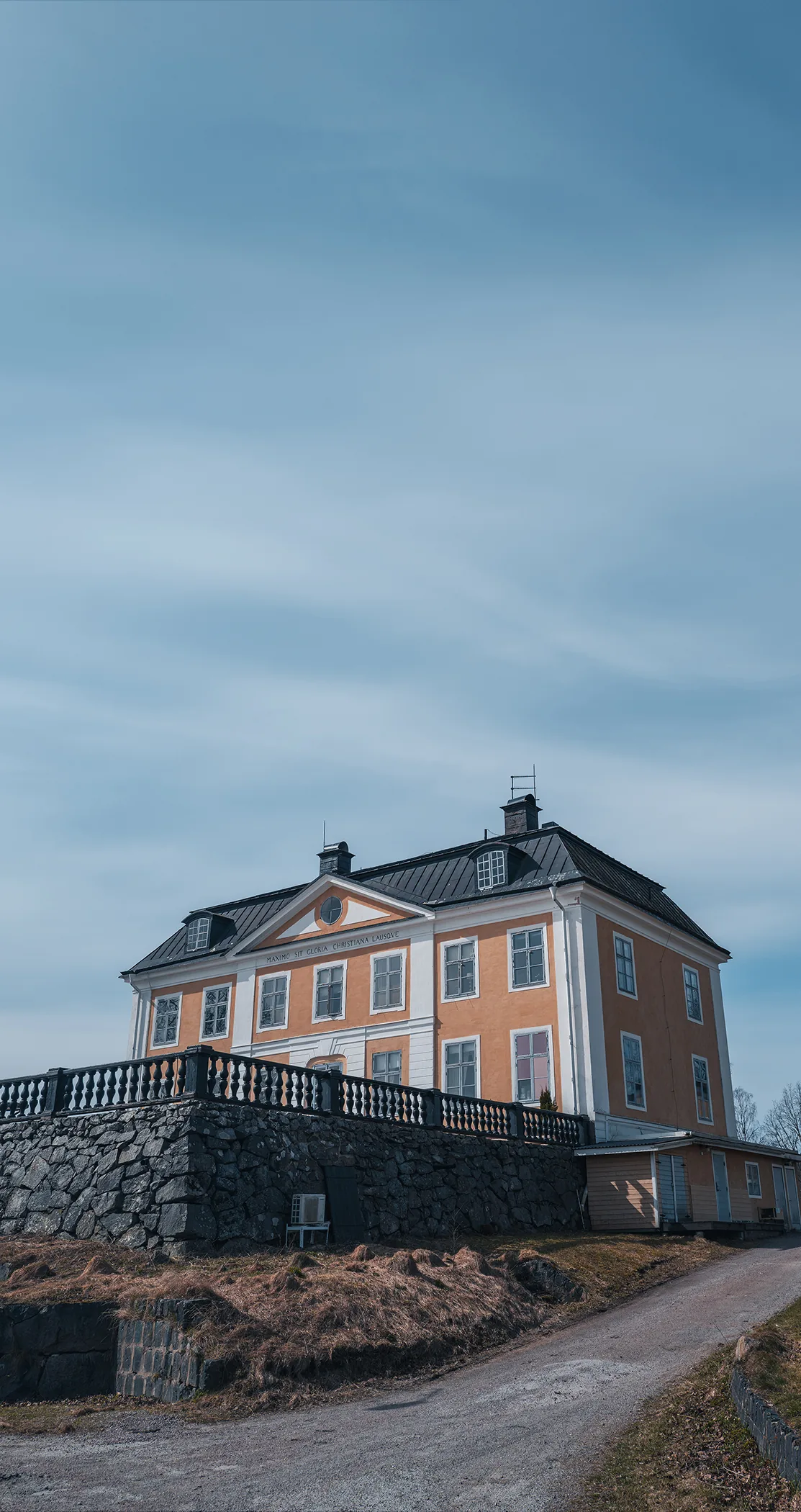 Manor house above a stone wall beside a gravel drive, Sweden